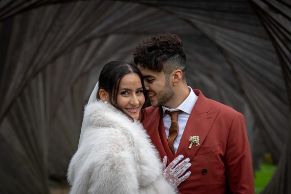 Un couple de mariés souriant, entouré d'une toile d'architecture moderne.